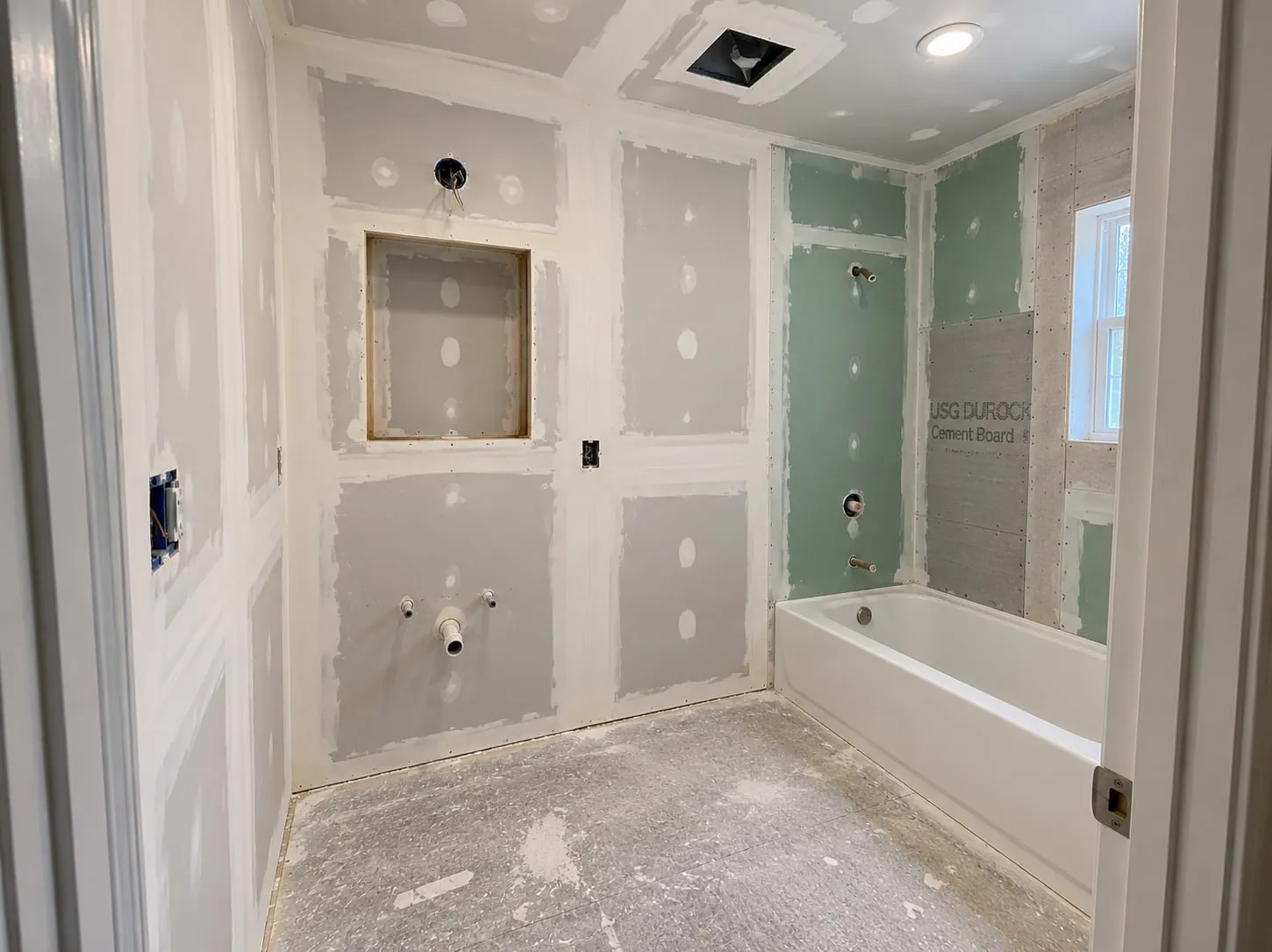 Bathroom remodel mid-job: green board and cement backer around the tub, the rest of the room taped and first-coated