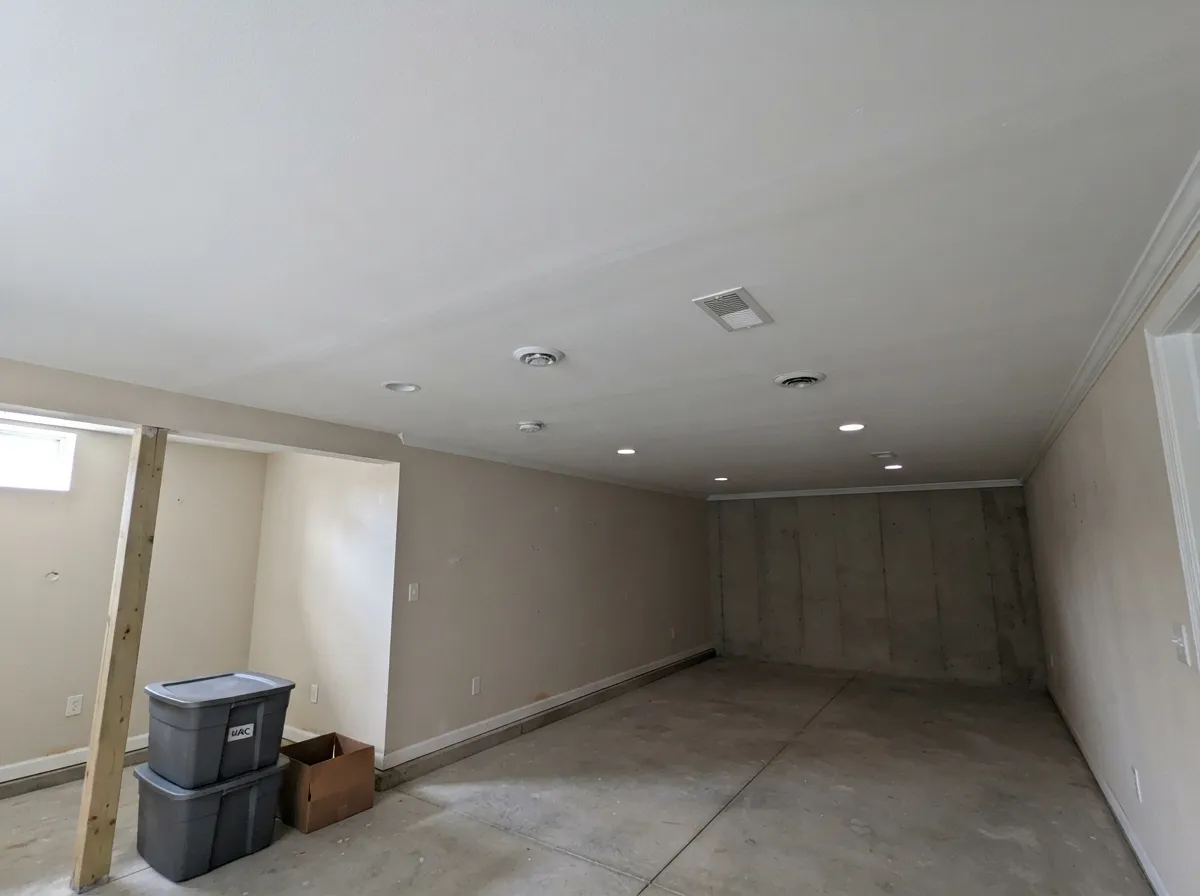 Long, flat basement ceiling hung with sag-resistant drywall, recessed lights installed